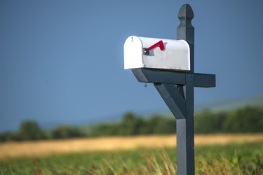 White Rural Mailbox With Red Flag On Blue or Gray Post