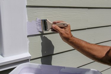 Man applying fresh paint on exterior of house