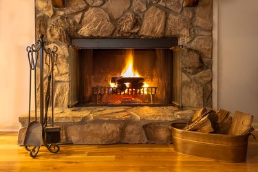 Stone fireplace with logs burning in a residential home.