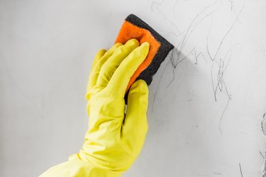 Cleaning child's pencil drawings off a white wall.