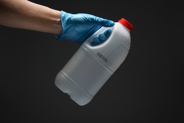 Holding a bottle with protective gloves.