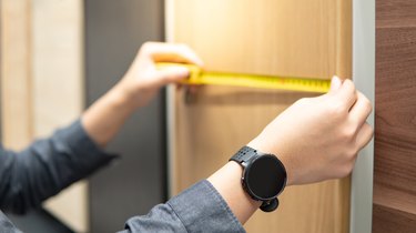 Male hand using tape measure on cabinet materials