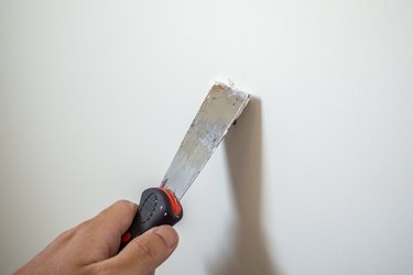 Man repairing crack white wall with spatula