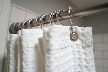 Decorative luxurious shower curtain on hooks.