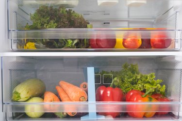 Produce drawers in refrigerator with a variety of vegetables and fruits.