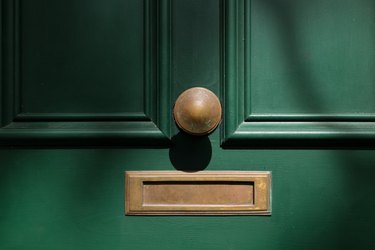 Old brass mail slot and door knob on a green door