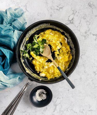 Scrambled eggs in a skillet on white, marble background