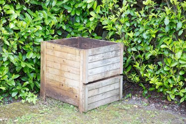 composter in the garden filled with freshly cut grass