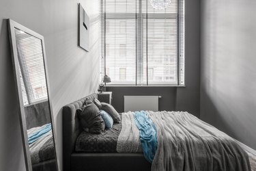 Small, gray bedroom with window and miniblinds.