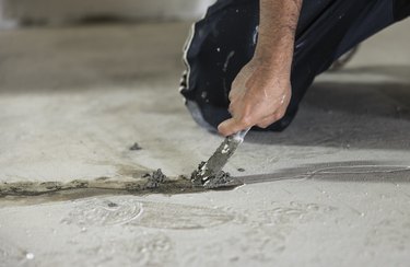 Basement waterproofing. Worker using hydraulic cement for sealing cracks in the basement floor.