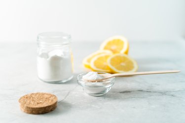 Eco friendly natural cleaners, jar with baking soda, lemon and wooden spoon on marble table background. Organic ingredients for homemade cleaning. Zero waste concept