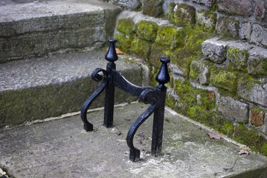 An antique black boot scraper affixed to the stone beneath a home's front stairs.