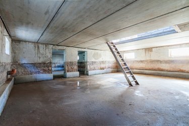 Concrete interior of unfinished garage basement apartment building trash colour with ladder and dlue day window light