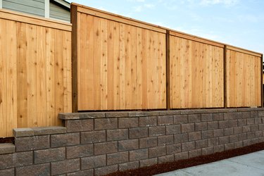 Wood fencing on concrete or stone retaining wall of home.