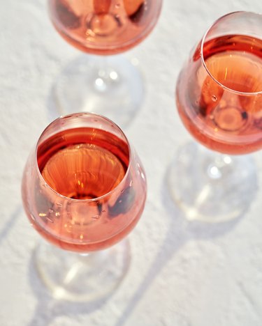 Rosé wine in three glasses on bright background with shadows