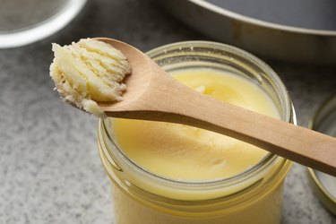 Glass jar and wooden spoon with yellow ghee