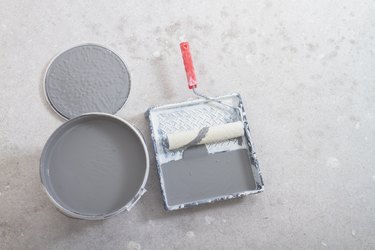 Gray paint in a jar, a tray with paint and a roller for painting works, preparation for painting the wall during apartment renovation