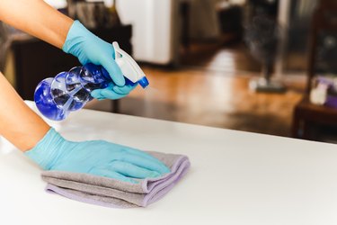 Hand with glove cleaning table with disinfectant spray and towel,Thailand