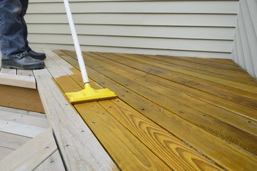 Applying stain to a deck.