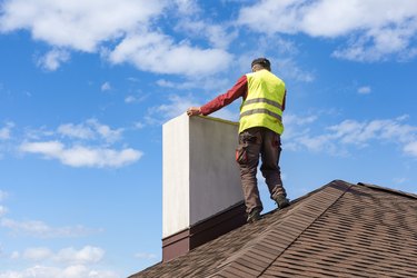 Man measuring chimney on roof top of new house under construction