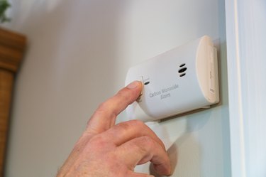 Man's Hand Testing Electrical Carbon Monoxide Alarm