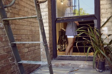 Young woman standing near window next to fire escape