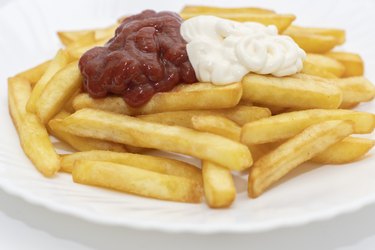 A plate of French fries with ketchup and mayonnaise