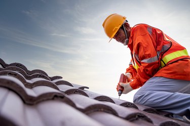 Construction worker install new roof, Electric drill used on new roofs with tiled roof