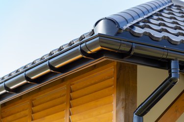 Corner of the new modern house with roof, gutter, and wooden shutter.