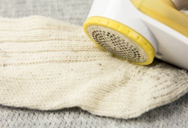 Removing sheaving lint fuzz from white woolen socks, wool clothes maintain concept.