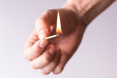 Burning match in the hand, flame of fire.