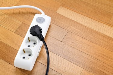 White extension cord with three outlets on wood floor