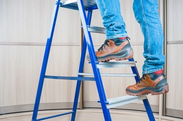 Handyman climbing on steel ladder indoors