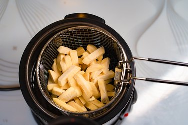 Basket of potatoes and deep fryer.