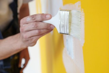 Painting with white paint over a yellow wall