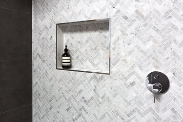 Shower shelf detail in wall of herringbone marble tiles