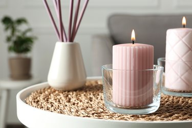 Burning candles and air reed freshener on table indoors, space for text