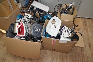 A huge lot of old, used, and broken spare parts from mass-produced electric home appliances, devices lying in cardboard boxes.