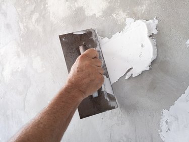 Using plastering tool for finishing old wall.