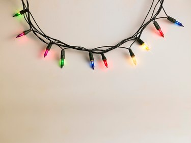 Colorful Illuminated String Lights Hanging On White Wall At Night
