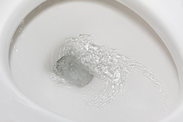 Motion blur of flushing water in toilet bowl. Plumbing, home repair, and water conservation concept.