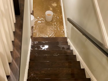 flood water flowing down staircase into house basement