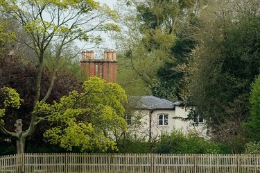 Frogmore Cottage nestled in the trees behind a fence