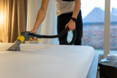 Mattress cleaning process. Man cleans bed from dirt and bacteria