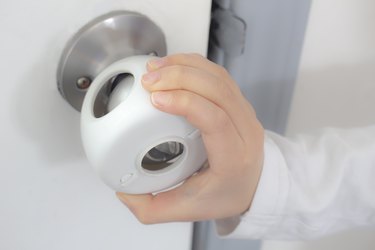 Child Proof Door Knob Covers over doorknob with a kid's hand trying to open the door