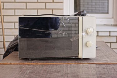 one old black white broken electric microwave