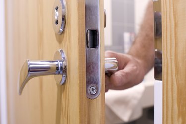 Close-up of a man's hand opening a wooden door