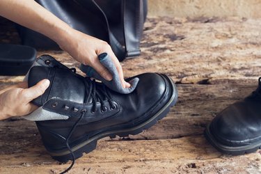 Cleaning boots on wooden background.