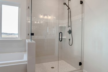 Bathroom shower stall with half glass enclosure adjacent to built in bathtub.