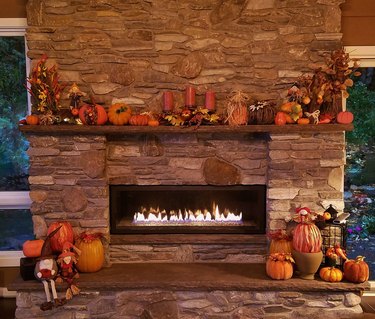 Large, Rustic Stone Fireplace All Glowing with Soothing Flames with Pumpkins and Autumn Holiday Decor